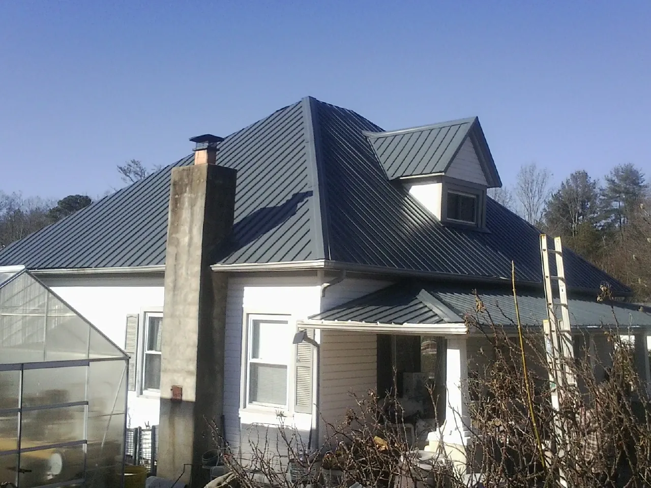 Dark blue standing seam metal roof on a white farmhouse with dormer — Slate & Tile Roof Repair by Roofing Brothers in Pine Hill
