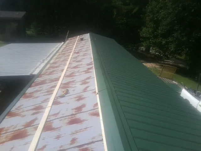 Old rusted panels beside newly installed green metal roofing — Wind Damage Roof Repair by Roofing Brothers in Pine Hill